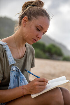Writer sitting and writing in journal at the beach