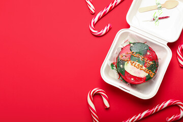 Plastic lunch box with Christmas bento cake and candies on red background