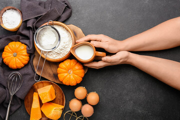Female hands with fresh ingredients for preparing pumpkin pie on black background