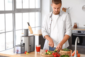 Young man preparing healthy vegetable juice in kitchen