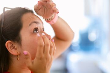 Young woman putting contact lenses