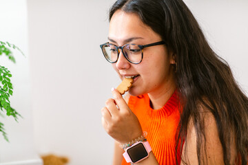 Young woman eating cookies at home