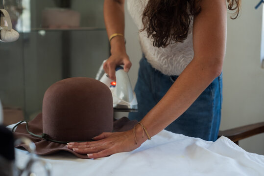 Anonymous woman using an iron to shape a fedora hat