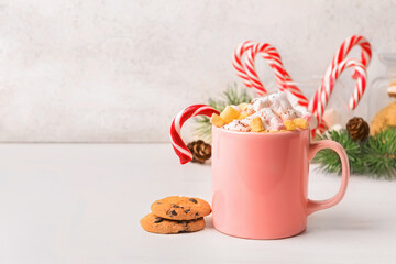 Cup of tasty cacao with marshmallows and candy cane on table
