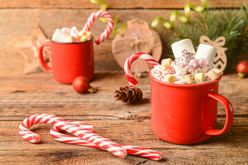 Cups of tasty cacao with marshmallows and candy canes on wooden background