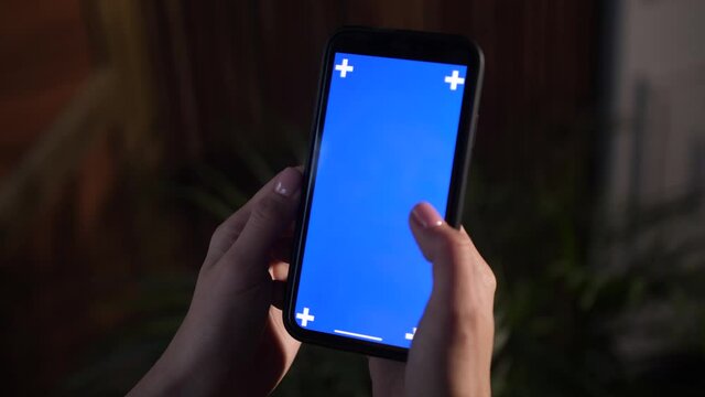 Closeup shoting of blue screen on iphone. Female holds in hands mobile cell phone device with moving interactive motion tracking points. Sliding, scrolling, zooming smartphone surface with fingers.
