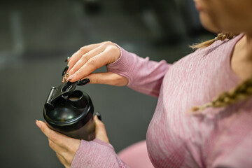 One unknown caucasian woman female athlete holding plastic bottle supplement shaker while training...