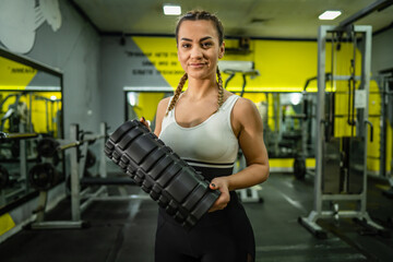 Fototapeta na wymiar One adult caucasian woman female athlete standing confident at gym looking to the camera waist up copy space holding foam massage roller