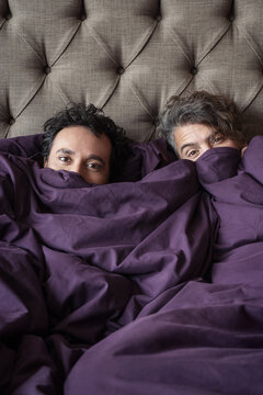 Gay couple picking out from under the blanket