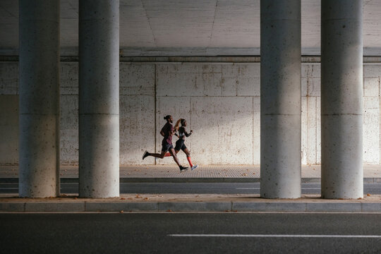 Athletes running under concrete bridge