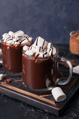 Glass cups of tasty hot chocolate with marshmallows on black background