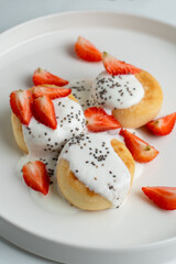 Golden roasted syrniki with strawberry and sour cream, appetizing photo of sweet russian breakfast