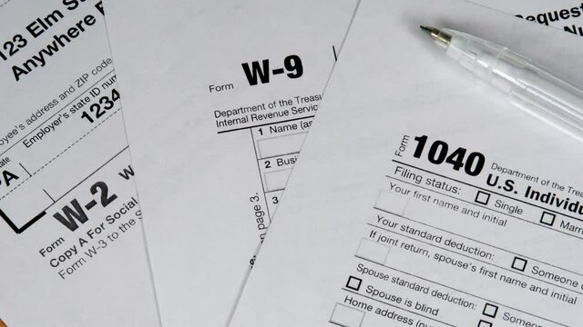 Different taxes forms for taxes payments with pen. Income tax return deduction refund. Savings, finances and economy concept. Form 1040 U.S. income tax return. W-2 and W-9 document