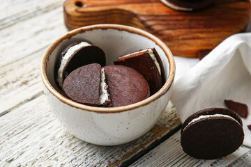 Bowl with tasty chocolate cookies on light wooden background, closeup