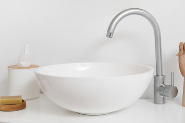 White sink with soap and tissue box near light wall