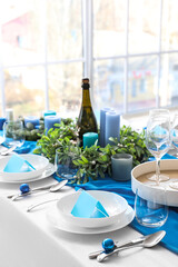 Dining table with beautiful setting for Christmas celebration and blank cards in room