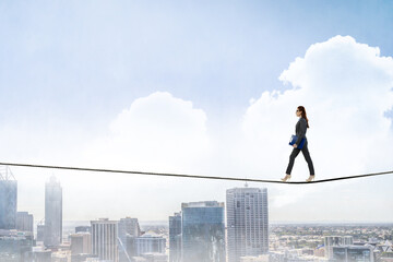 Image of businesswoman balancing on rope. Risk concept
