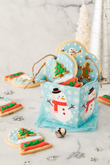 A gift box filled with snow globe cookies with twine ties for hanging on a tree.