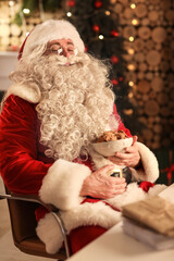 Obraz premium Happy Santa Claus with tasty cookies at home in evening