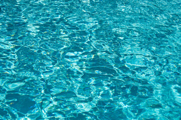 Water background. Blue water, ripples and highlights. Texture of water surface and tiled bottom.