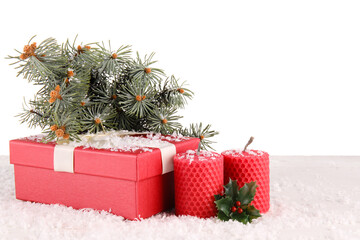 Beautiful composition with Christmas gift boxes, fir branches, snow and candles on table against white background