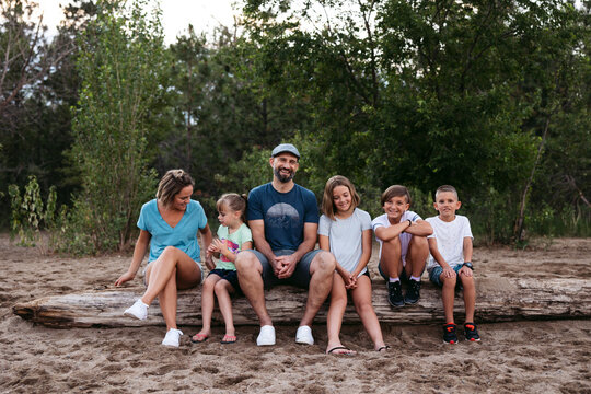 Large Family Sitting Together On Log.