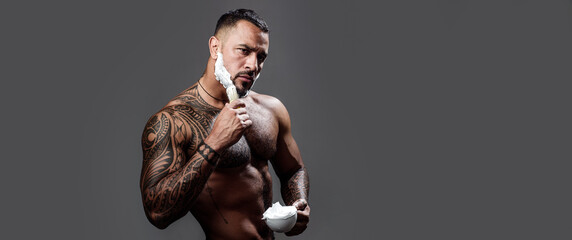 Sexy bearded man shaving with blade razor, unshaved bearded gay. Barber with straight razor, barbershop. Shaving in barber shop. Templates banner. Shaving cream, foam. Banner for hair salon.