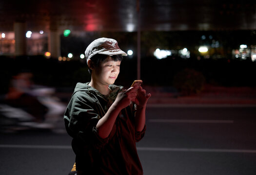 Asian woman looking at mobile phone on busy street