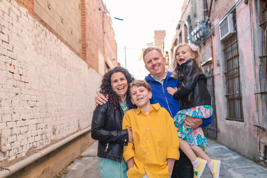 Happy family of four in alley