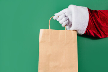 Trendy craft package in Santa's hands on green background. Sale, contactless, holidays concept.