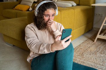 Teenager using phone and headphone at home