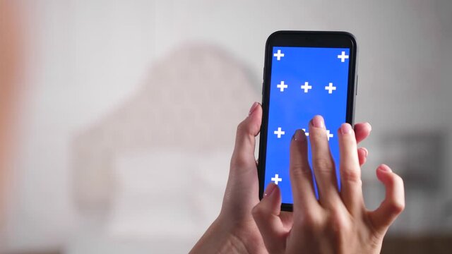 Closeup shots of blue screen on iphone. Woman holds in hands mobile phone device with moving interactive motion tracking points. Touching, tapping smartphone surface with fingers, zooming in and out