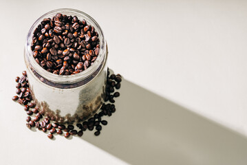 roasted coffee beans in a glass jar casting a shadow