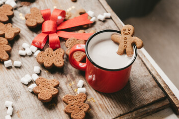 ginger man in a cup of cocoa with a big red bow on a wooden background, top view. Various Christmas sweets with a cup of cocoa on the table. Christmas flatlay