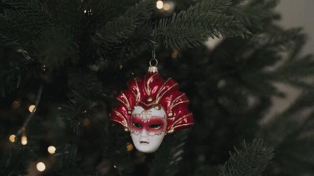 Close-up of woman's hands decorating Christmas tree. Venetian mask
