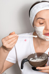 A girl, engaged in spa treatments, puts a liquid cosmetic mask on her face