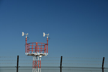 Wind vane and anemometer with blue sky background.