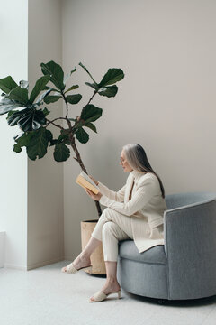 Senior woman reading a book in minimal style interior