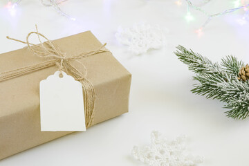 Close up of vintage craft gift with rope and blank label isolated on white background. Spruce branch, garland, christmas gift