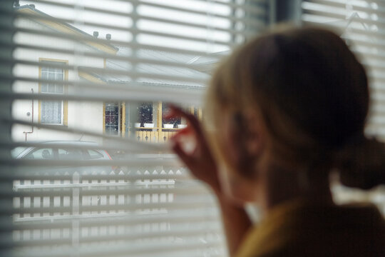 Female peeking through shutters