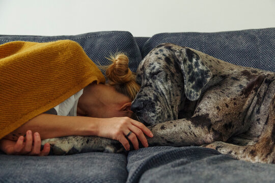 Woman and dog sleeping on couch