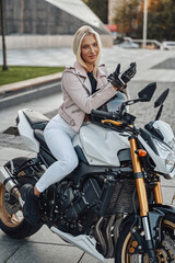 Naklejka na ściany i meble Trendy woman biker posing on modern urban motorcycle