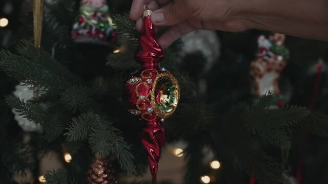 Close-up of woman's hands decorating Christmas tree wist antique retro toy
