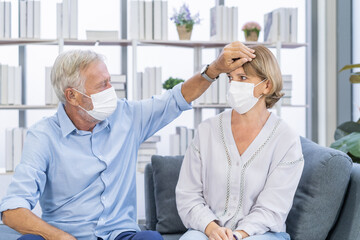 Obraz premium Sick, ill Caucasian senior, mature couple elderly family wearing face mask with weakness, headache have fever, flu. Husband check temperature on body of wife. Health care on virus seasonal.