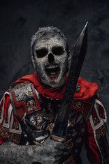 Centurion zombie with scary face holding sword against dark background