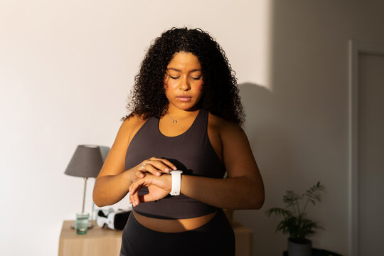 Woman looking at smart watch in sportswear at home