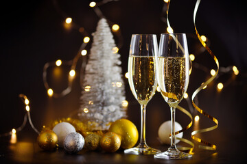 Two champagne glasses and christmas decorations on a dark festive background. Happy New Year.