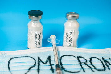 A medical mask labeled Omicron, two vials of vaccine from the new strain, and a syringe. Vaccine...