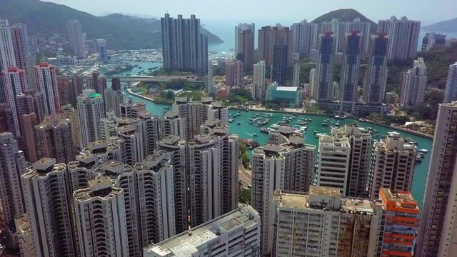 Aerial Ships Moored In Sea Amidst City, Drone Flying Forward Over Buildings - Hong Kong, China