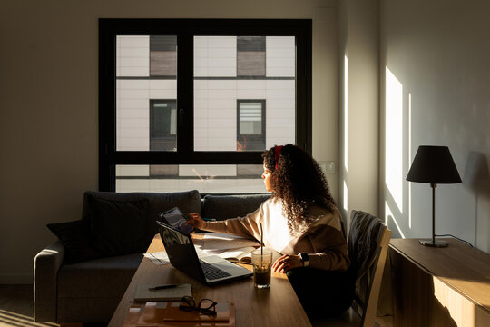 Latin woman working in office at sunset